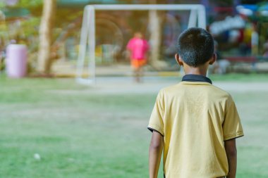 Asyalı erkek kamu futbol alanında gol topu tekme uygulama.