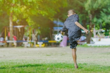 Asyalı erkek kamu futbol alanında gol topu tekme uygulama.