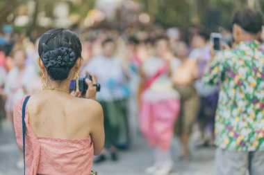 Back view of female in Thai dress  take a photo of a Thai dance parade in Songkran festival