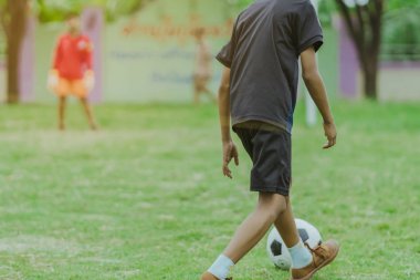 Asyalı erkek kamu futbol alanında gol topu tekme uygulama.