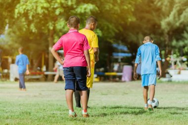 Asyalı erkek kamu futbol alanında gol topu tekme uygulama.