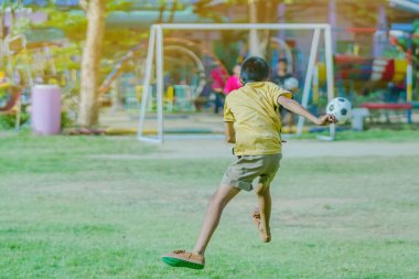 Asyalı erkek kamu futbol alanında gol topu tekme uygulama.
