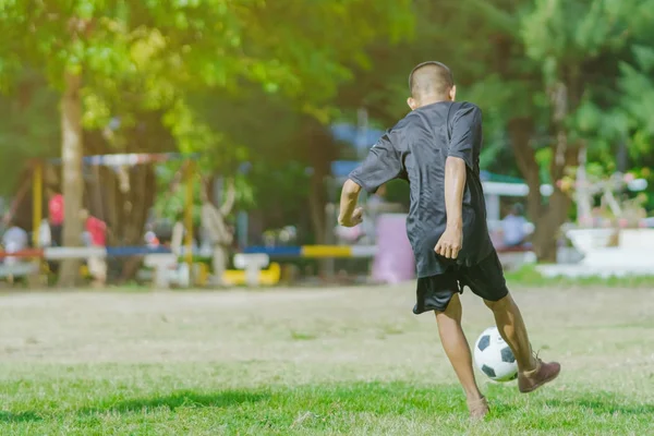 Asyalı erkek kamu futbol alanında gol topu tekme uygulama.
