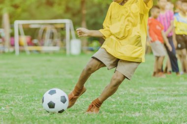 Asyalı erkek kamu futbol alanında gol topu tekme uygulama.