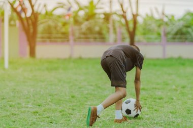 Asyalı erkek kamu futbol alanında gol topu tekme uygulama.