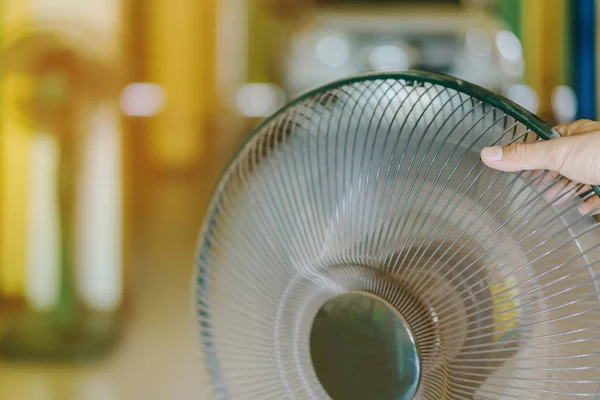 Mano del joven toque y ajuste en las parrillas delanteras de ventilador eléctrico para un buen viento — Foto de Stock