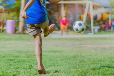 Asyalı erkek kamu futbol alanında gol topu tekme uygulama.