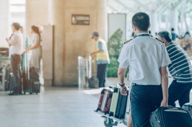 Büyük silindir bagajı olan yolcular, havaalanı varış terminalinden arabanın almasını beklemek için ayakta dururlar..