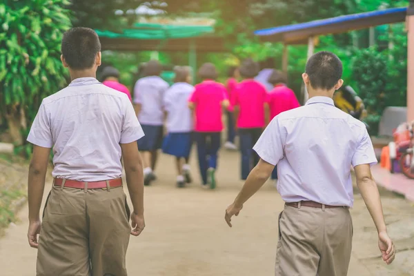 Счастье студенты мужского пола ходить позади своих подруг в школе . — стоковое фото