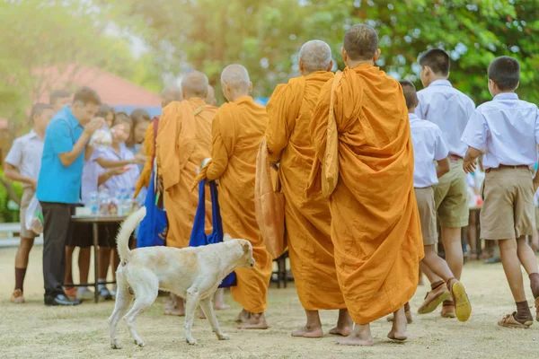 Professores e estudantes juntos fazem o mérito de dar oferendas de comida a um monge budista — Fotografia de Stock