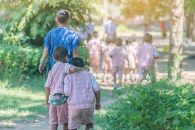 Anaokulu çocuk öğle yemeğinden sonra sınıfa geri kadın öğretmen ve arkadaşları sonra yürümek.