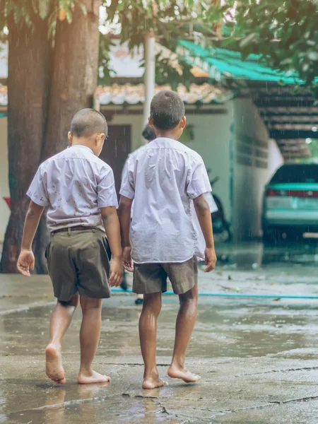 Meninos estudantes saem da sala de aula para caminhar na rua após forte chuva na escola . — Fotografia de Stock