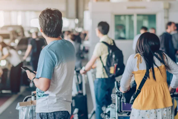 Passengers with big roller luggage stand to wait for the car to pick up at airport arrival terminal. — Stock Photo, Image