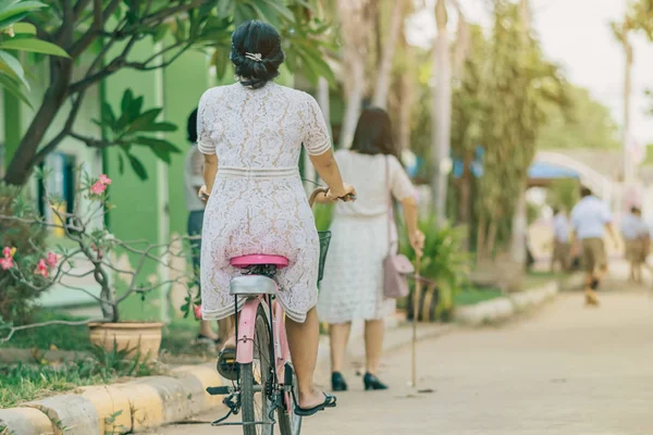 Back view of female teacher rides bicycle to teach students at classroom. — Stock Photo, Image