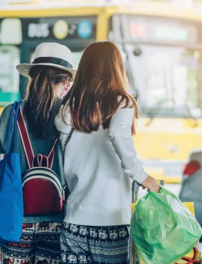 Büyük silindir bagajı olan yolcular, havaalanı varış terminalinden arabanın almasını beklemek için ayakta dururlar..