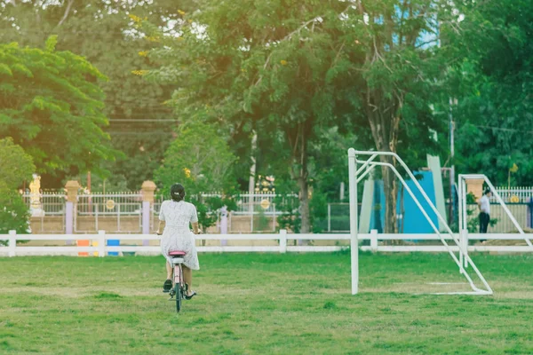 Rückansicht einer Lehrerin fährt Fahrrad auf Fußballplatz — Stockfoto
