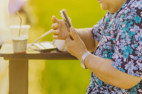 Mujer mayor sentarse para descansar y esperar el tiempo para tomar fotos de la puesta del sol — Foto de Stock