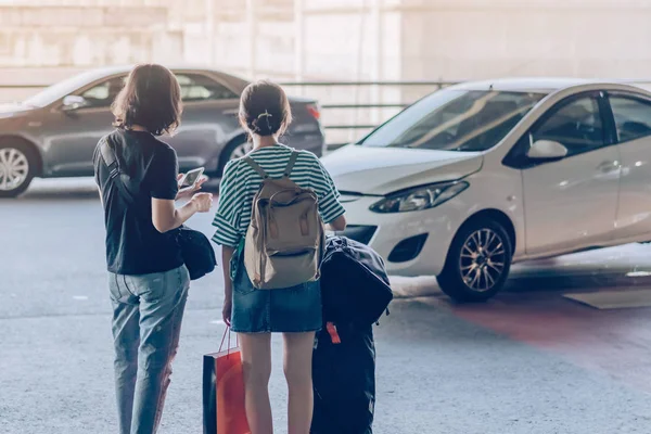 Passageiros com grande suporte de bagagem de rolo para esperar o carro para pegar no terminal de chegada do aeroporto . — Fotografia de Stock