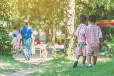 Anaokulu çocuk öğle yemeğinden sonra sınıfa geri kadın öğretmen ve arkadaşları sonra yürümek.