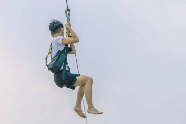 A male tourist flying on a zipline aka flying fox across the lake at Pattaya Floating Market, Thailand. — Stock Photo, Image