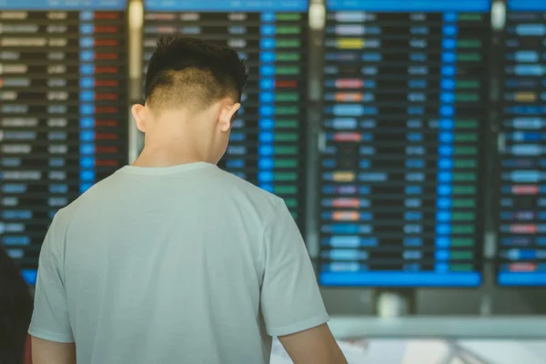 Pasażerowie patrzą na pokład informacji powietrznej i sprawdzą swój lot na międzynarodowym lotnisku — Zdjęcie stockowe