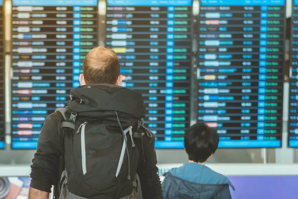 Passengers looking at the flight information board and checking their flight in international airport — Stock Photo, Image