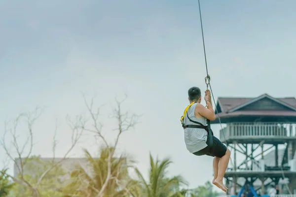 Een mannelijke toerist vliegen op een Zipline aka Flying Fox over het meer op Pattaya Floating Market, Thailand. — Stockfoto