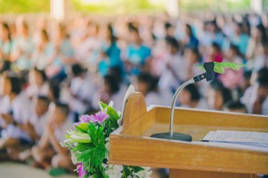 Okul konferans salonundaki podyumdaki masaüstü mikrofon standına yerleştirilmiş yapay yaprak.
