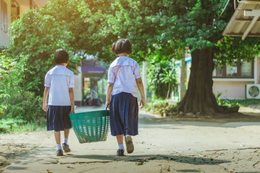 Kız Öğrenciler atık yığını için sınıftan çöp kaldırmak için yardım