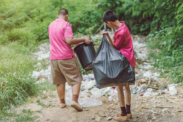Estudiantes masculinos ayudan a eliminar la basura del aula para amontonar residuos . — Foto de Stock