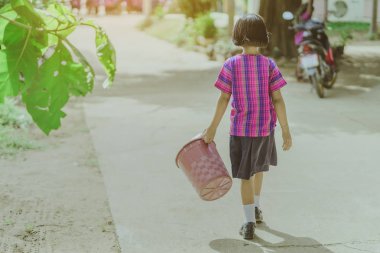 Kız Öğrenci atık yığını için sınıftan çöp kaldırmak