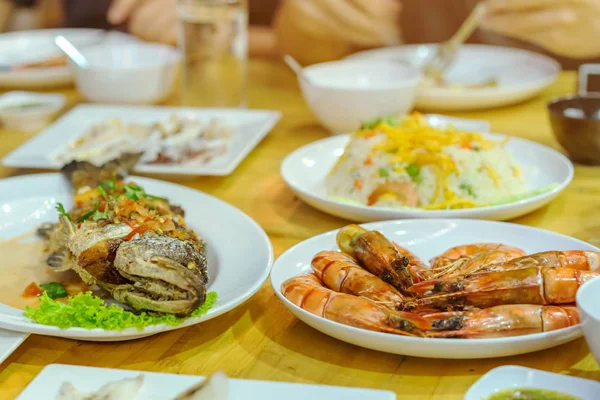 Keluarga bahagia menikmati makan dengan berbagai hidangan seafood saat makan malam . — Stok Foto