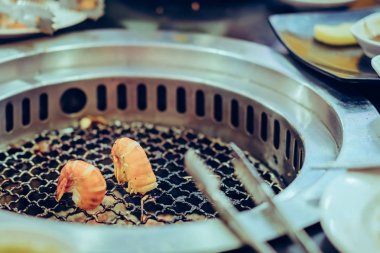 İnsanlar restoranda dumansız ızgarada et pişiriyor..