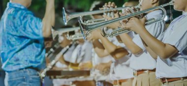 Arkadaşları ile erkek öğrenci gece sahnede performans için grup ile trompet darbe.