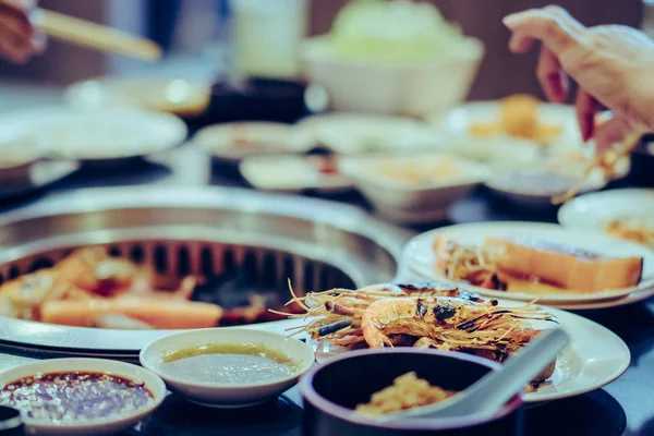 Personas asando carne en una parrilla de barbacoa sin humo en un restaurante. — Foto de Stock