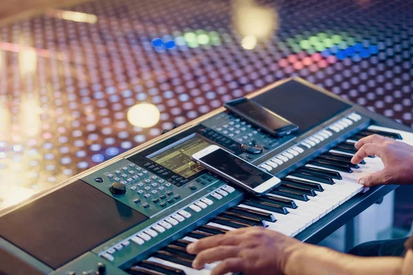Musicista suonare sintetizzatori tastiera elettronica utilizzando smartphone come linee guida per la riproduzione sul palco del concerto — Foto Stock
