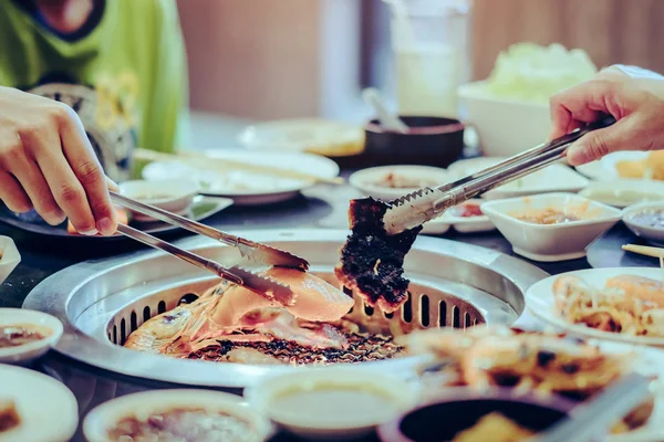 Personas asando carne en una parrilla de barbacoa sin humo en un restaurante. —  Fotos de Stock