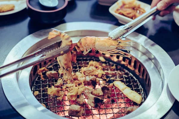 İnsanlar restoranda dumansız ızgarada et pişiriyor..