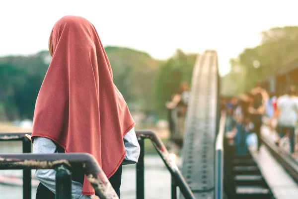 Visão traseira da mulher muçulmana relaxar e admirar a bela paisagem à noite na Ponte do Rio Kwai — Fotografia de Stock