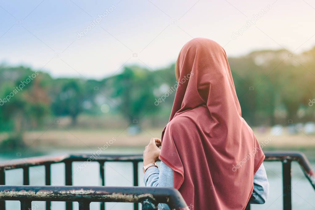 Back view of Muslim woman relax and admire the beautiful scenery in the evening on The Bridge of the River Kwai