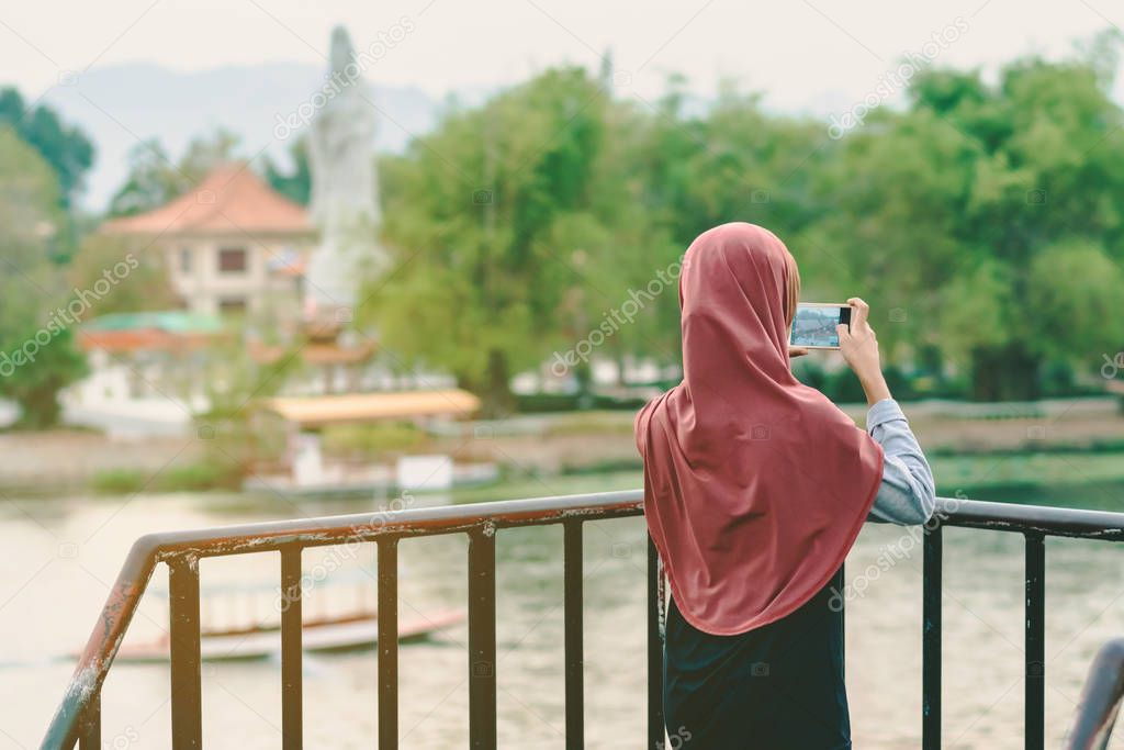 Back view of Muslim woman relax and admire the beautiful scenery in the evening on The Bridge of the River Kwai