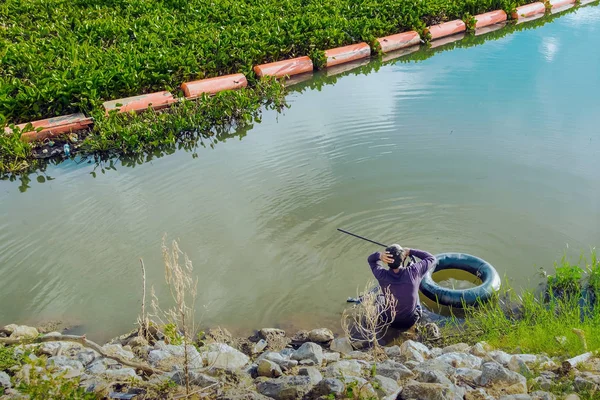 Jäger Fischer mit Speerspitze auf Rettungsring sucht abends unter Wasser nach Fischen. — Stockfoto