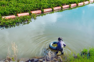 Bir zıpkınla zıpkın tutan avcı balıkçı akşam vakti balık aramak için suyun altına bakar..