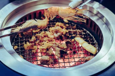 İnsanlar restoranda dumansız ızgarada et pişiriyor..