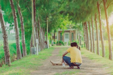 Halk parkındaki çam ağaçlarının altında yürüyen ve fotoğraf çeken çift..