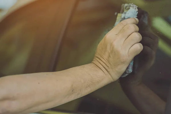 Close up to hand of male worker use wet newspapers to clean the glass part of the car — Stock Photo, Image