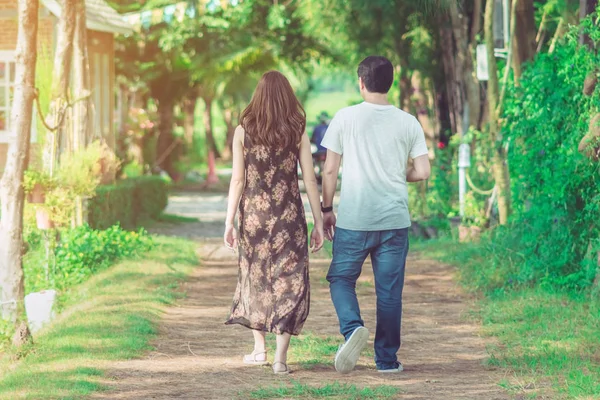 Halk parkındaki çam ağaçlarının altında yürüyen ve fotoğraf çeken çift..