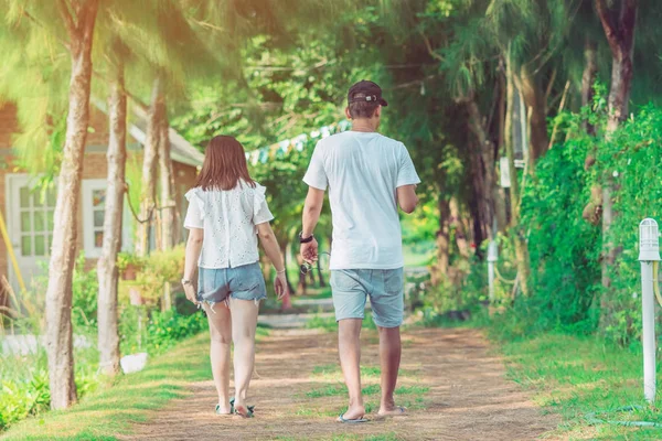 Halk parkındaki çam ağaçlarının altında yürüyen ve fotoğraf çeken çift..