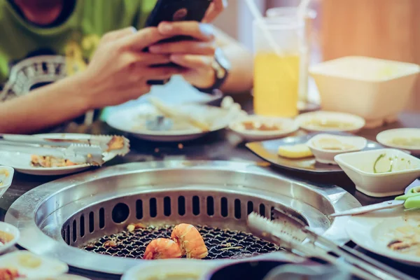 Menschen grillen Fleisch auf einem rauchlosen Grill in einem Restaurant. Selektiver Fokus auf Garnelen. — Stockfoto