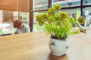 Dekorasyon için masanın üzerindeki yapay bitkiler veya plastik ağaçlar ve kahve dükkanındaki müşteriler için hoş geldin..